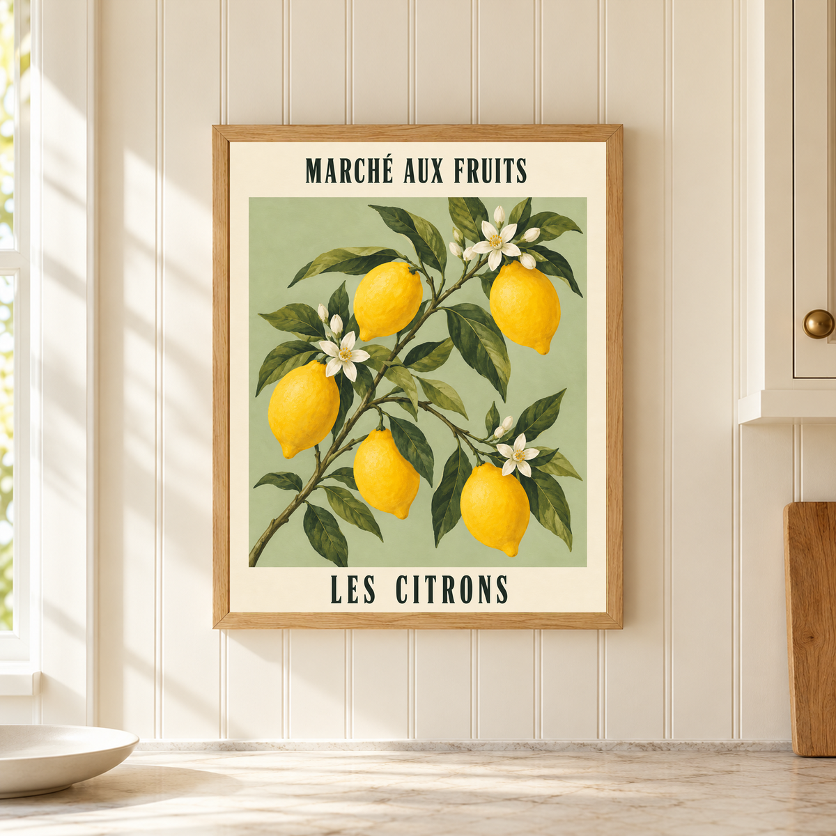 Close view of French Lemon Market in a light oak frame on ivory kitchen beadboard, showing the complete lemon illustration and French lettering above a pale counter.